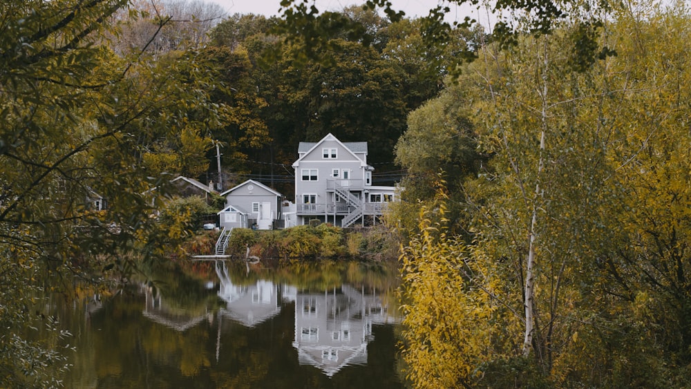 white concrete house near green trees and lake during daytime