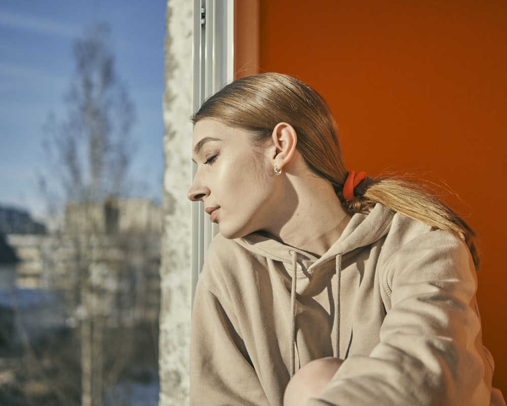 woman in gray coat looking at the window