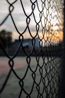 grey metal fence near green grass field during daytime
