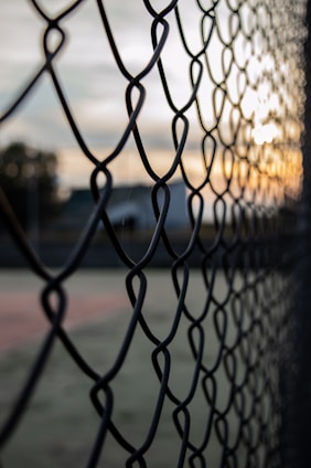 grey metal fence near green grass field during daytime