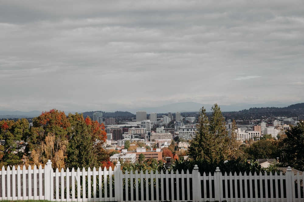 white wooden fence near city buildings under white cloudy sky during daytime