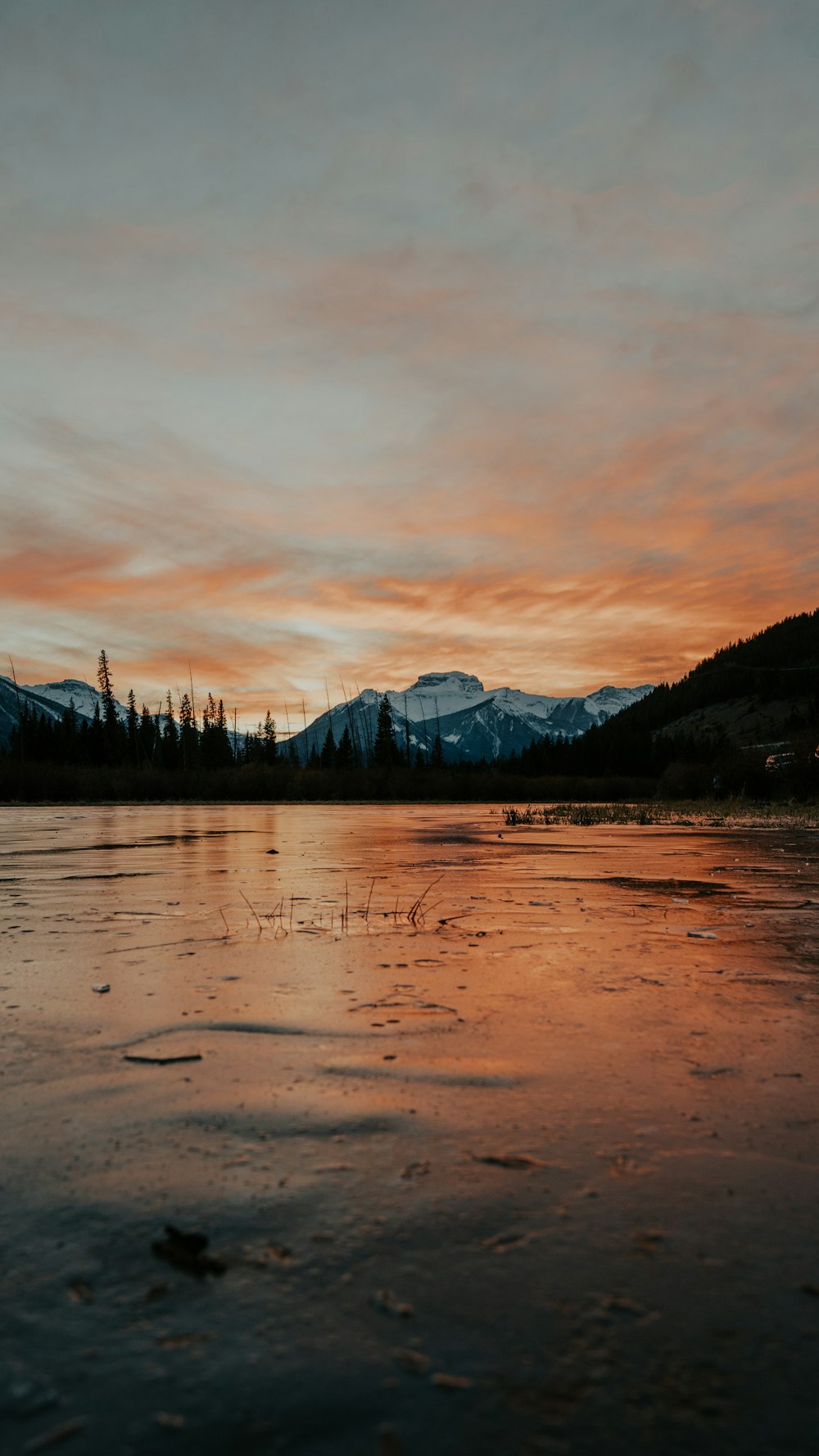 body of water near mountain under cloudy sky during daytime