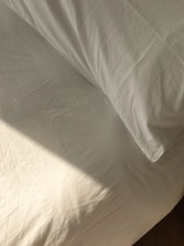 Freshly made bed with crisp linens in a sunlit bedroom ready for new guests.