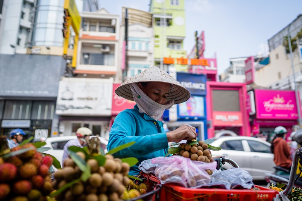 woman in blue long sleeve shirt and brown straw hat holding red fruit