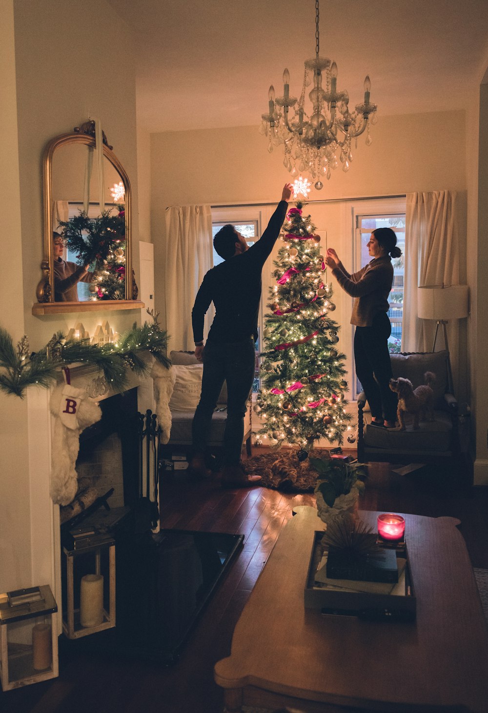 man in black suit standing near christmas tree