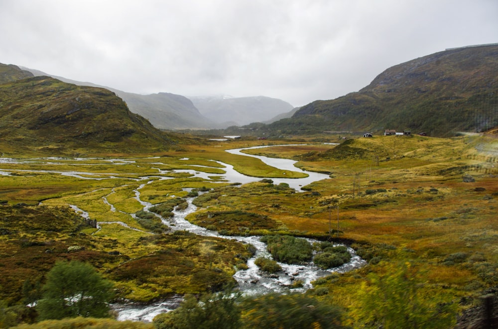 green grass field and mountain under white clouds