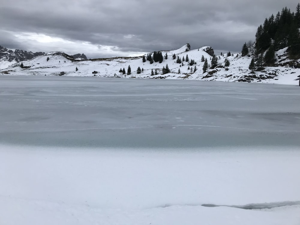 snow covered field under cloudy sky during daytime