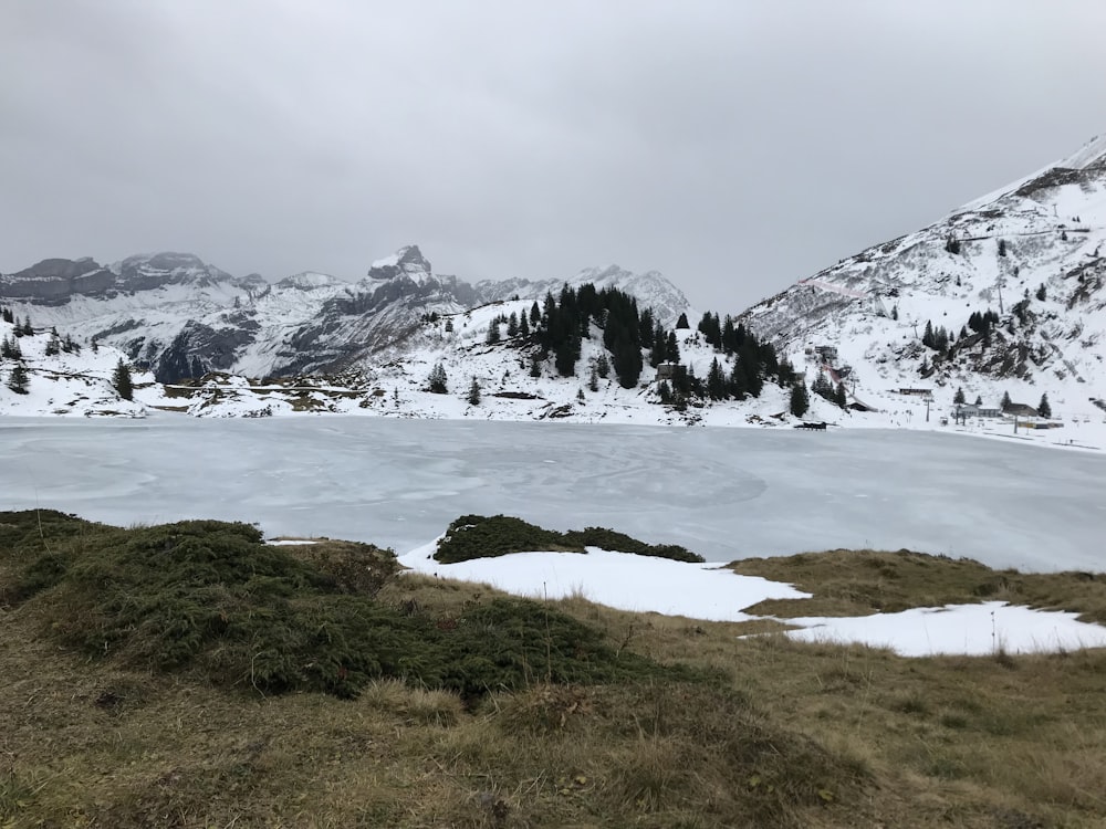 snow covered mountain near body of water during daytime