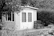 A robust wendy house with a lockable door, surrounded by garden tools and boxes.