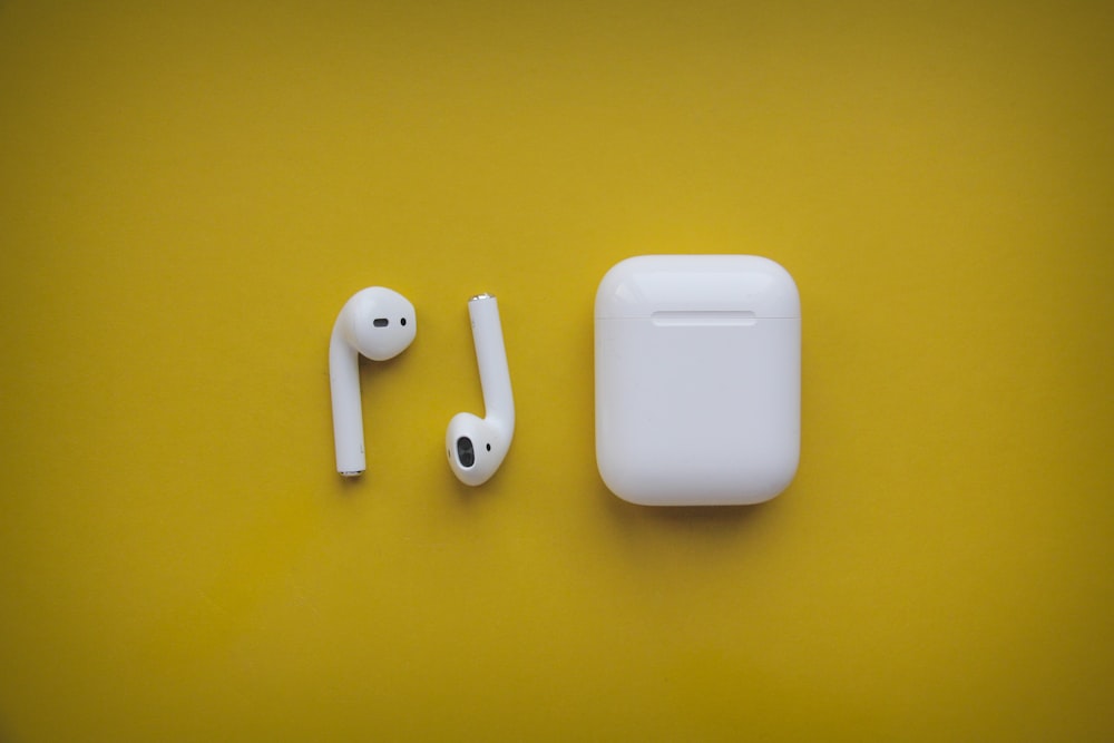 airpods brancos da maçã na superfície amarela