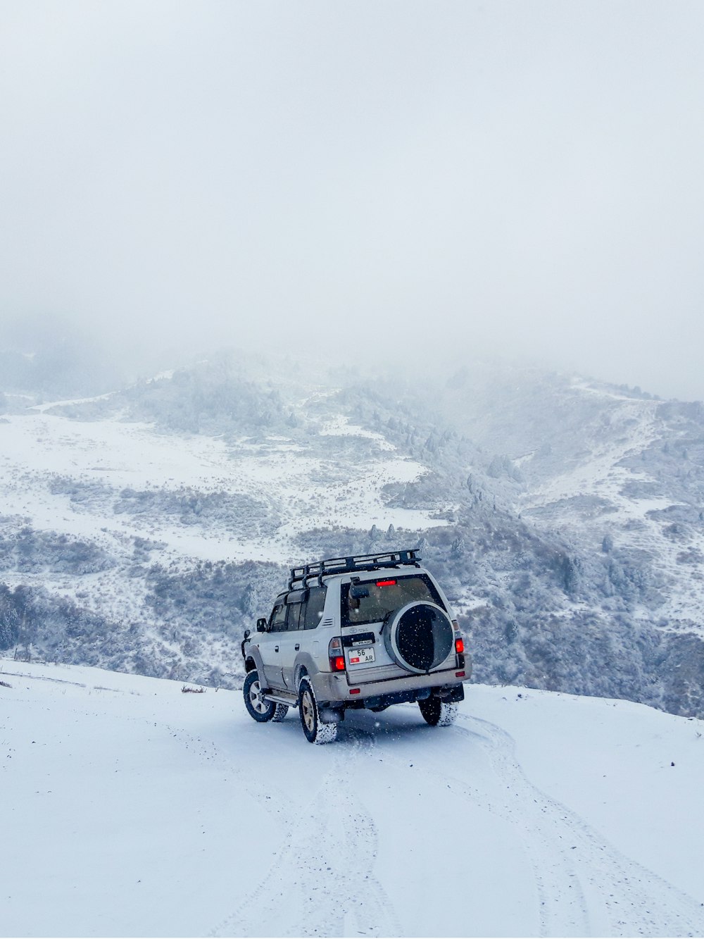 SUV blanco y negro en una montaña cubierta de nieve durante el día