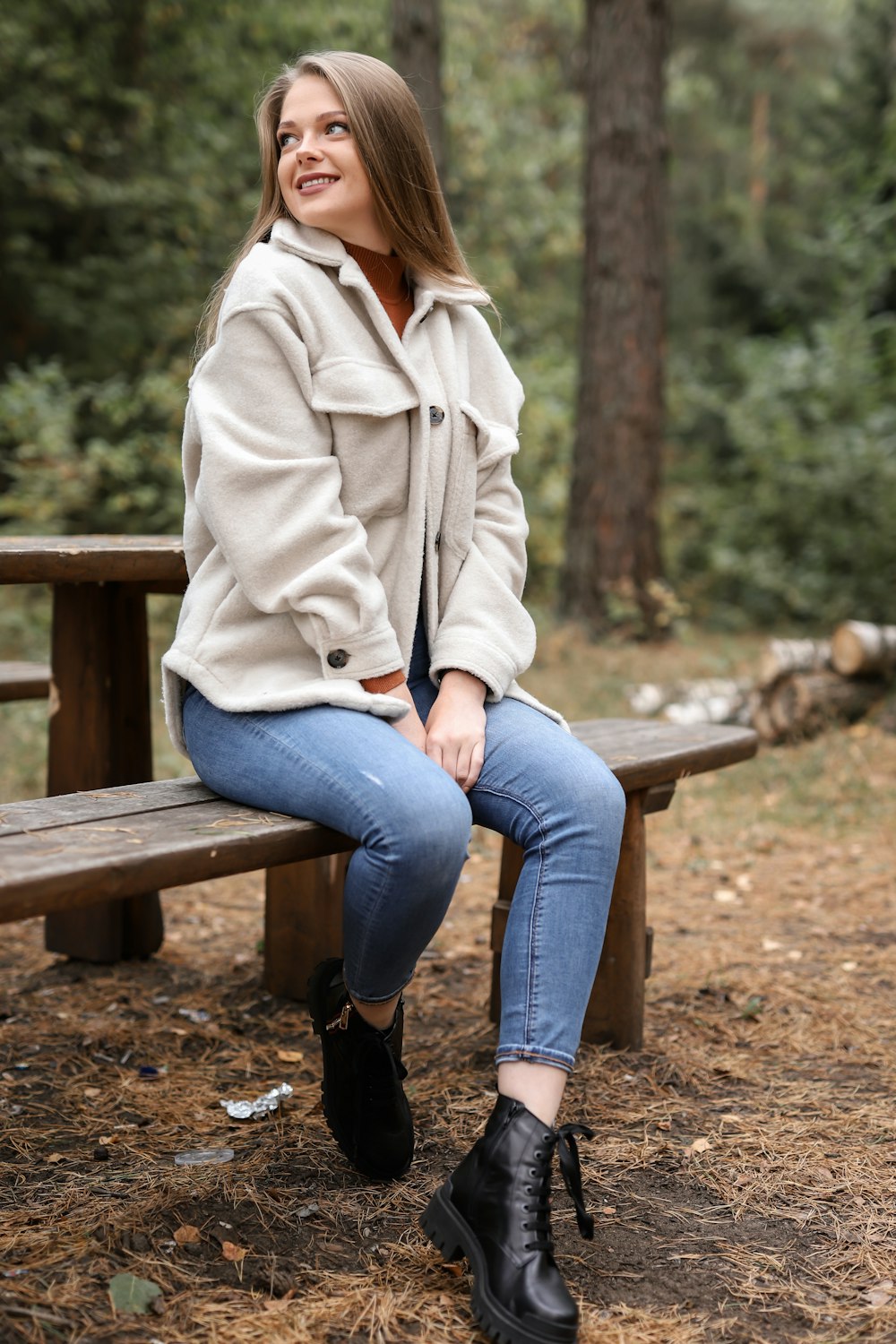 woman in white coat sitting on brown wooden bench during daytime