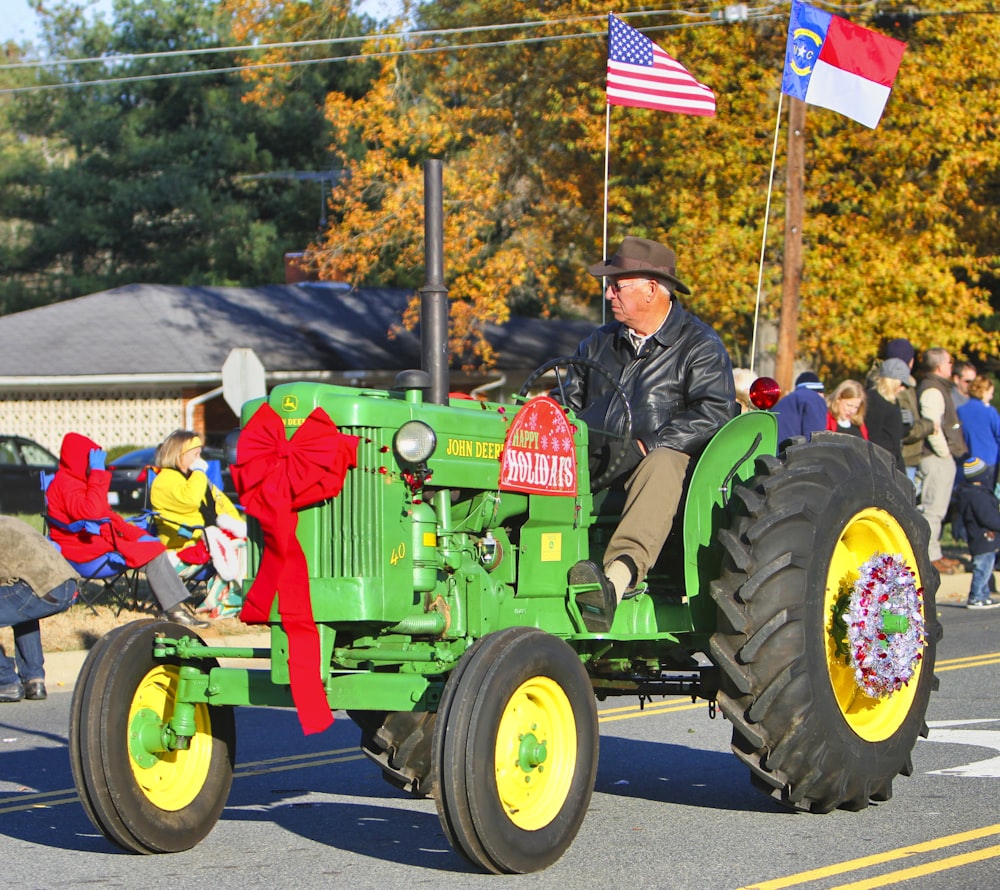 man in blue jacket riding green tractor during daytime