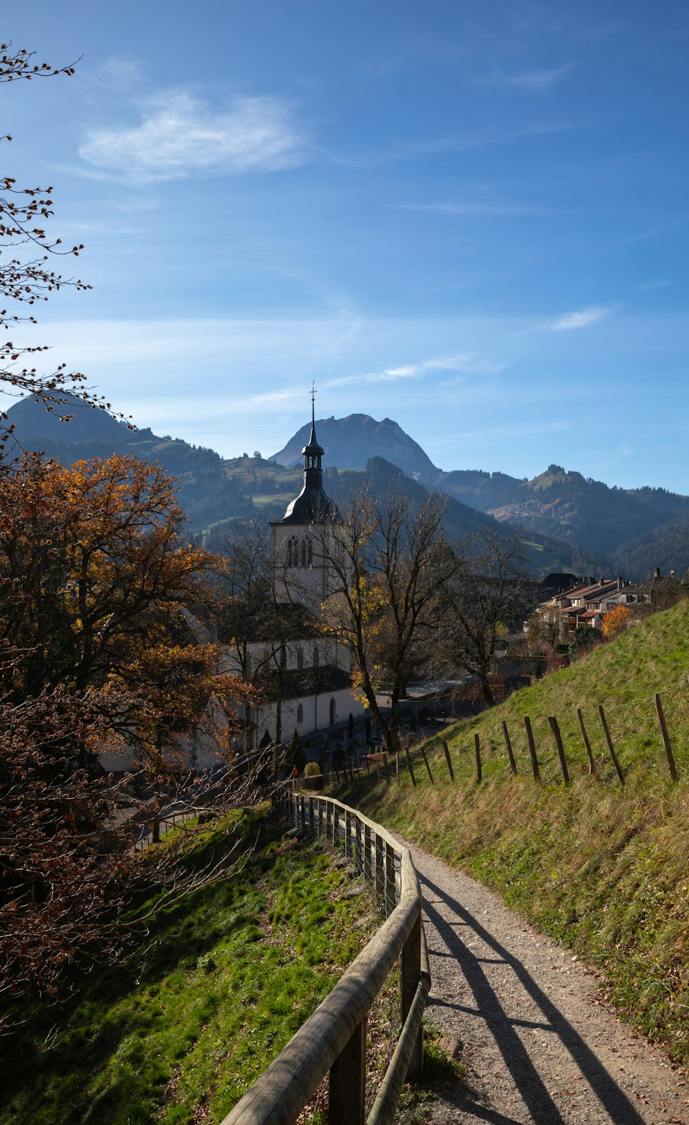 Casa marrone e bianca sul campo di erba verde vicino alla montagna sotto nuvole bianche e cielo blu