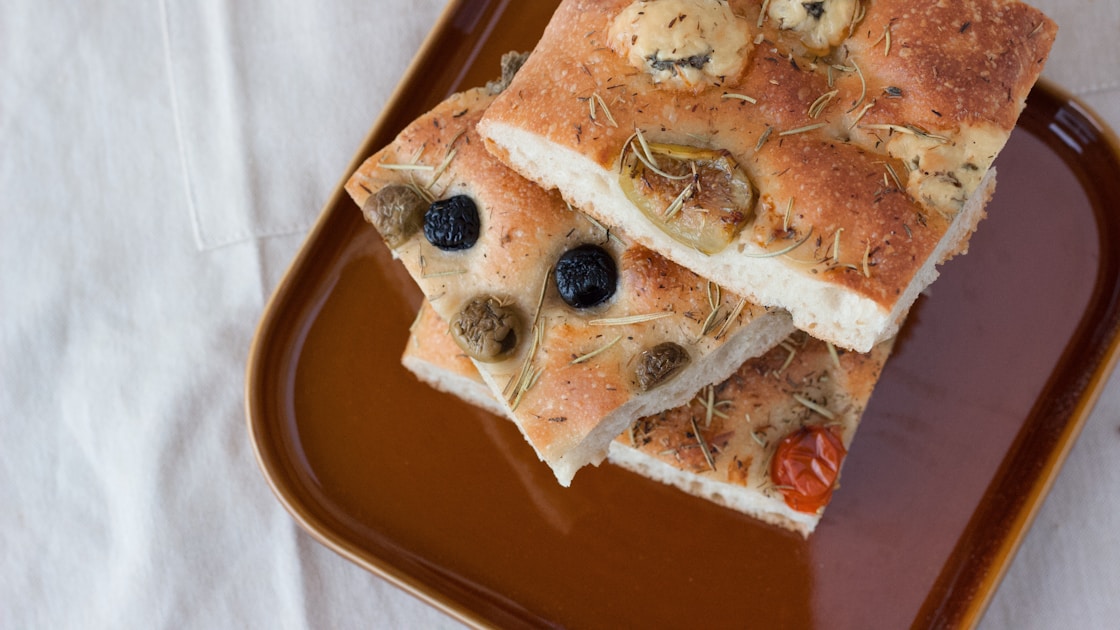Focaccia aux olives et romarin dorée sur planche en bois