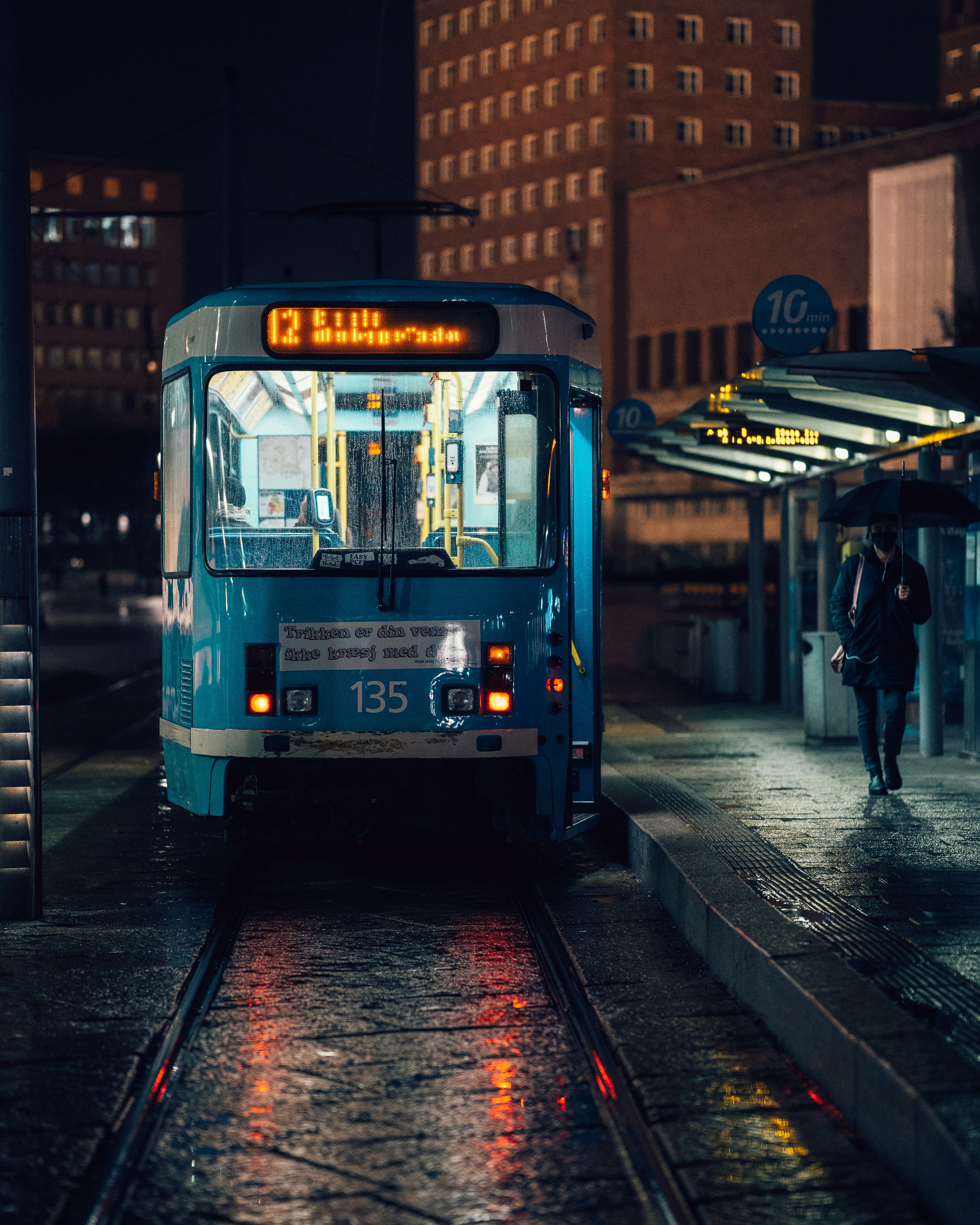 a blue bus driving down a street next to a tall building