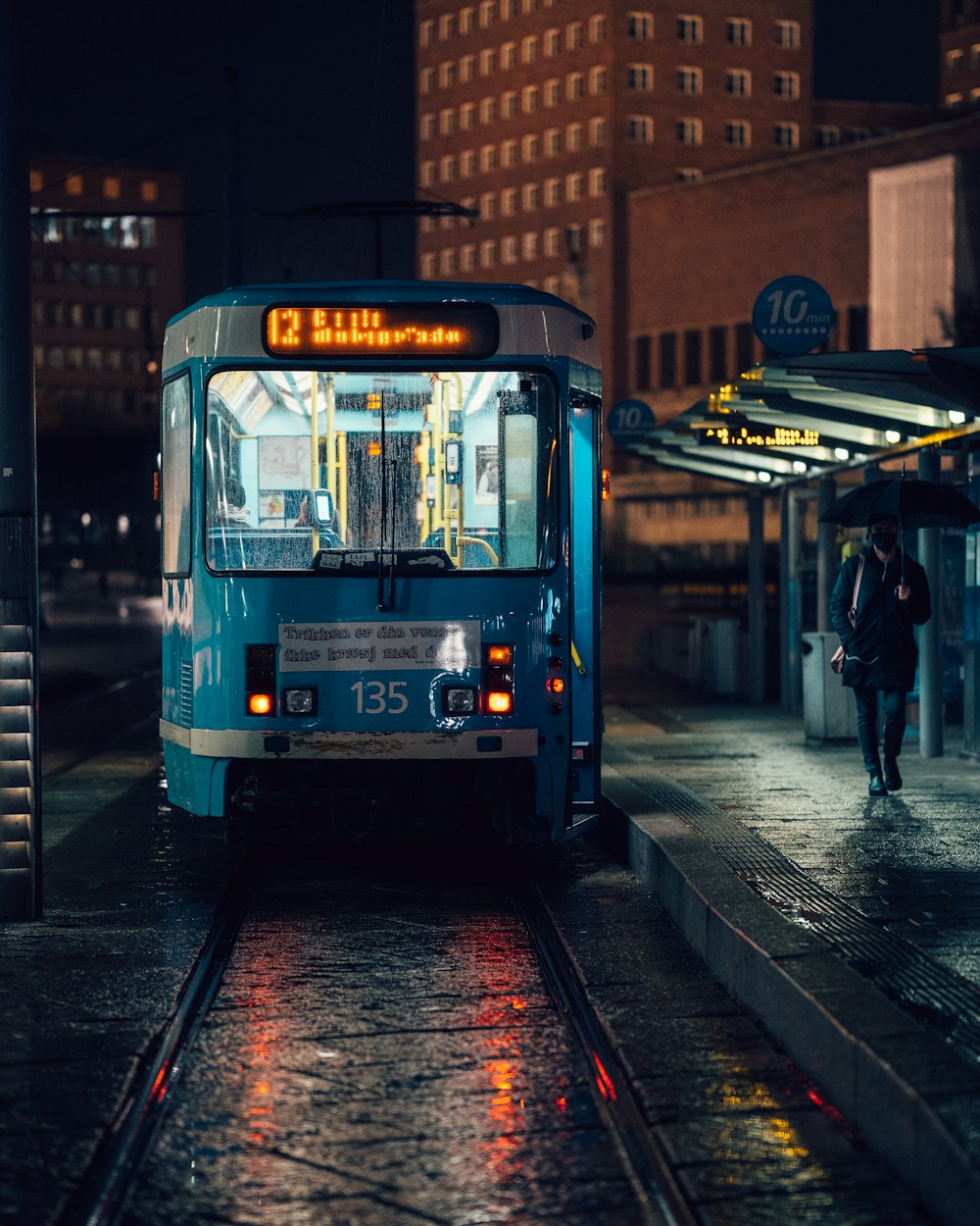 a blue bus driving down a street next to a tall building