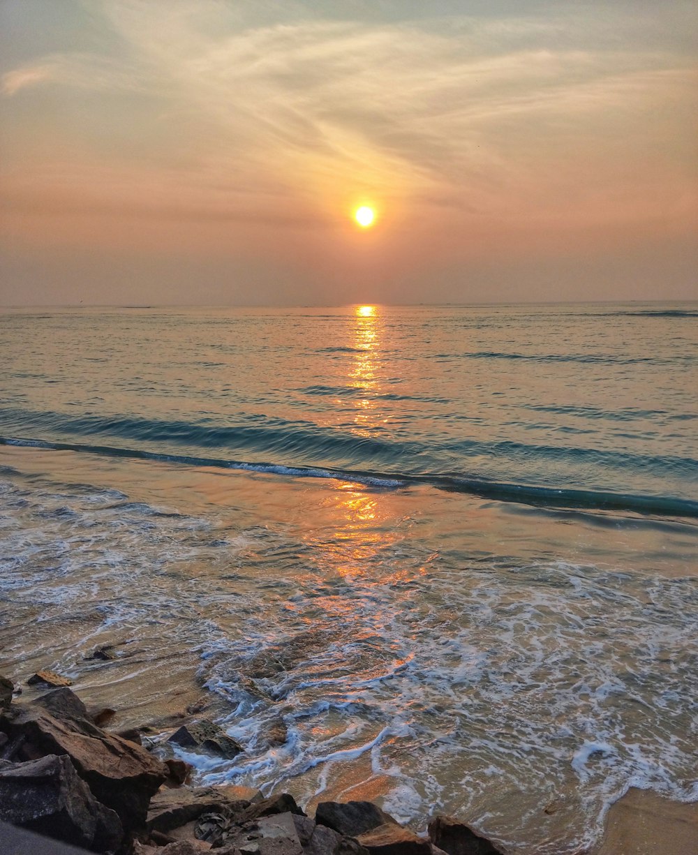 ocean waves crashing on shore during sunset