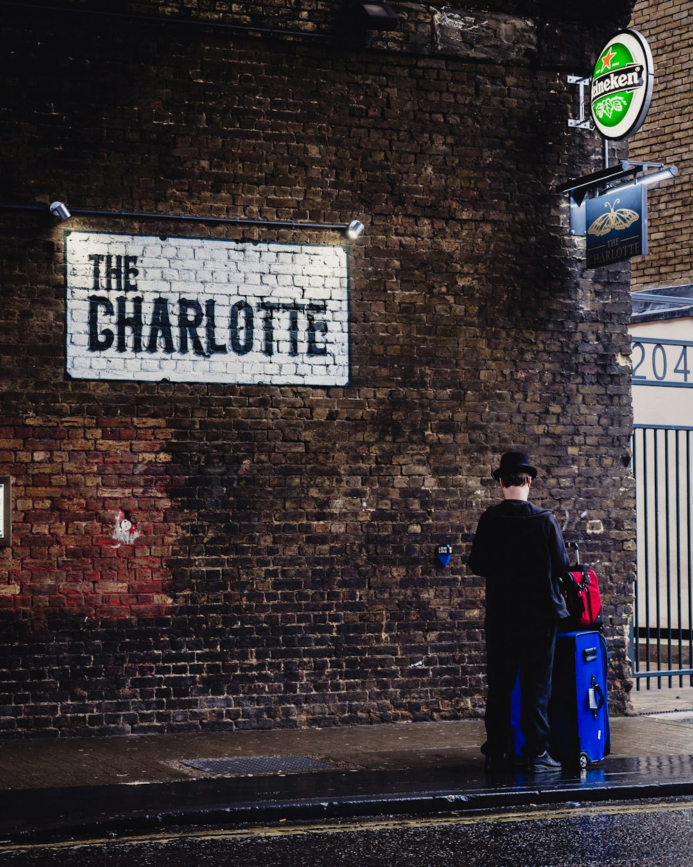 man in black jacket standing near brick wall