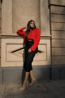 Casual chic: a woman in a soft beige sweater and jeans leaning against a textured brick wall
