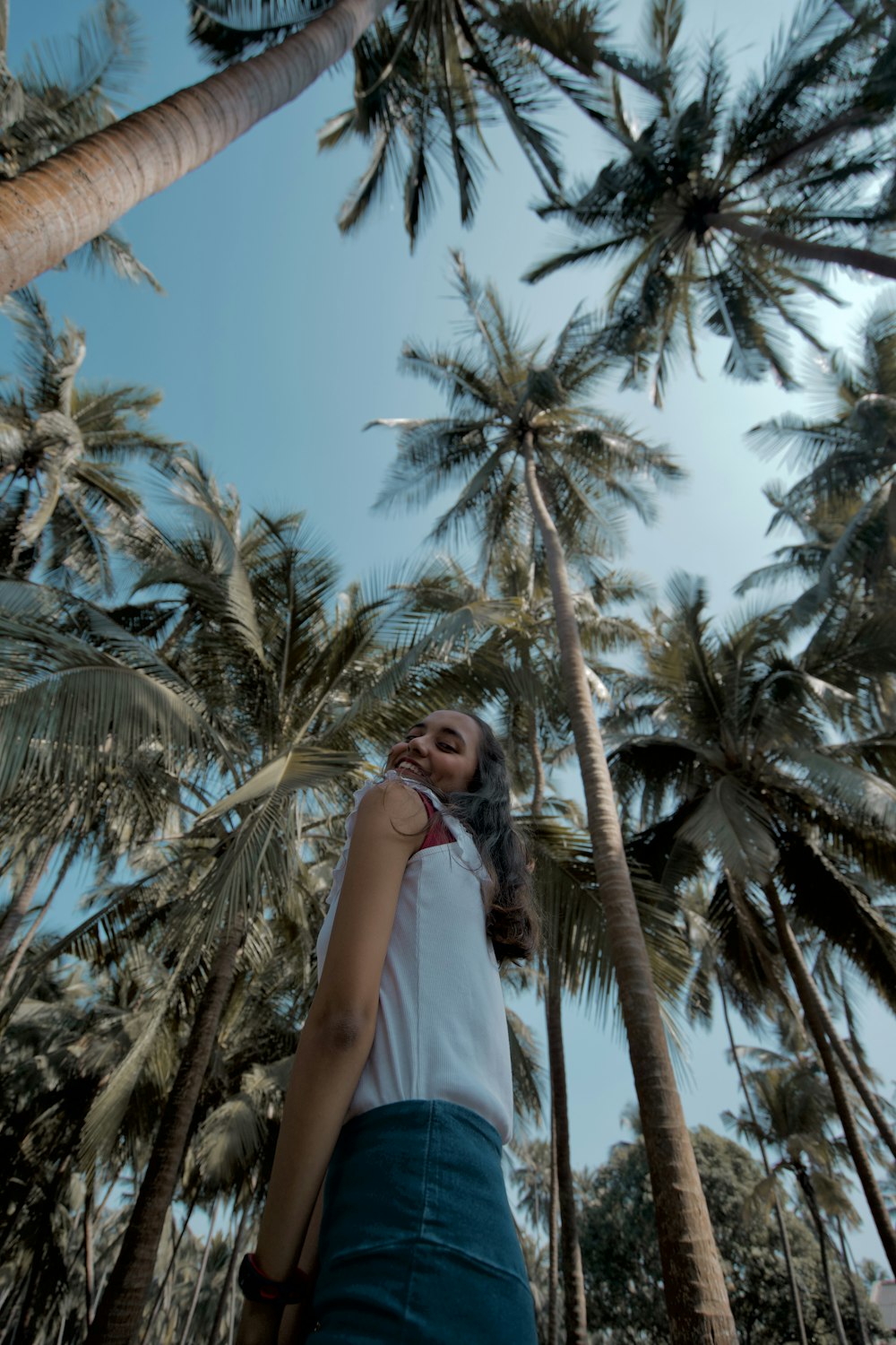 woman in white sleeveless dress standing near palm tree during daytime