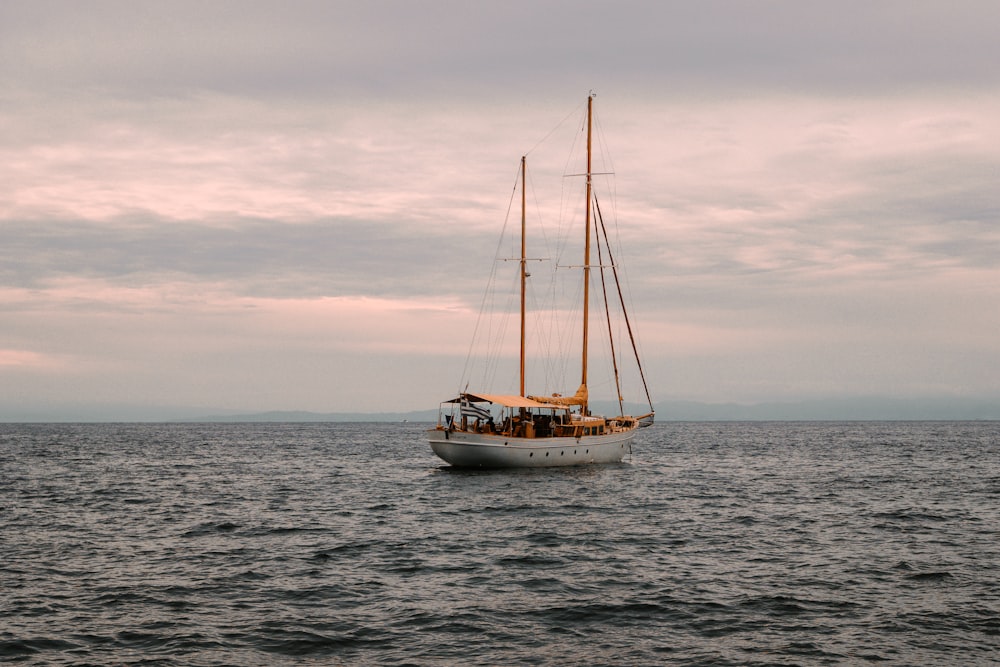 weißes und braunes Boot tagsüber unter weißen Wolken auf See