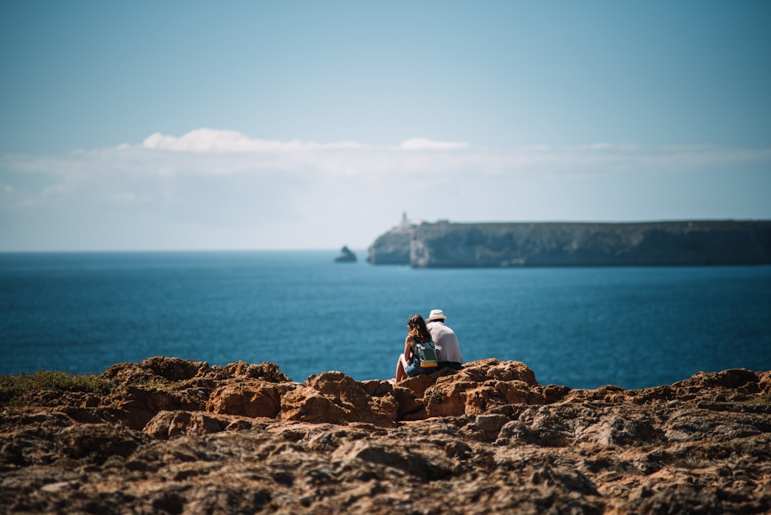 person sitting on rock near body of water during daytime