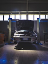 Workshop technician inspecting a car's exhaust system in a garage.