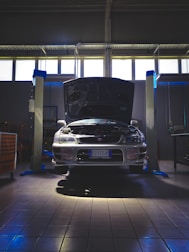A mechanic inspecting a car engine under bright garage lights.