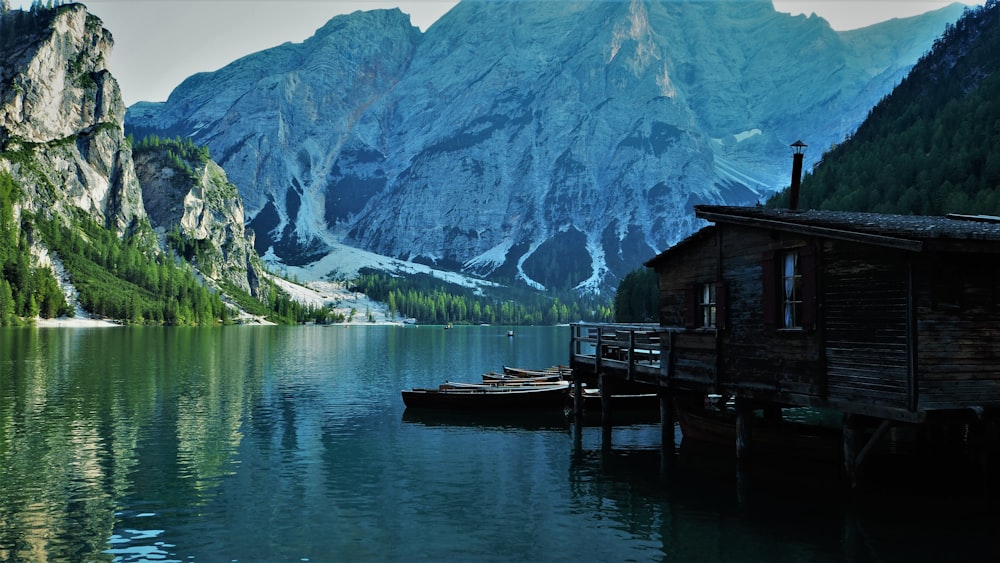 brown wooden house on lake near mountain