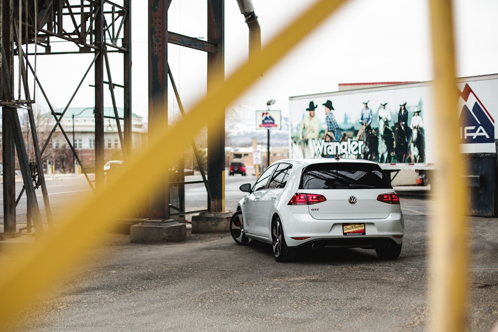 white sedan parked near black metal fence during daytime