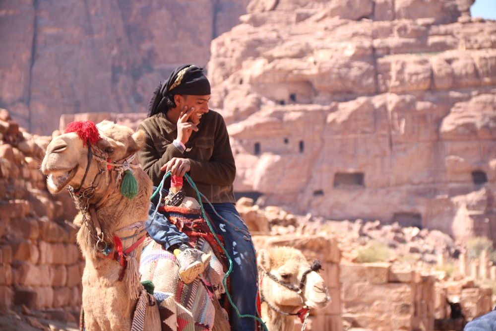 homme au casque noir chevauchant un chameau pendant la journée