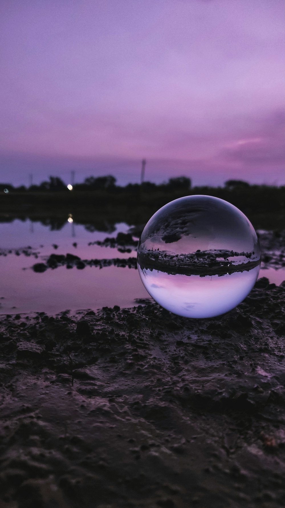 clear glass ball on black sand near body of water during daytime