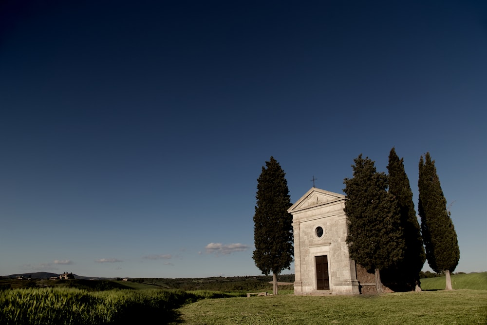 Chiesa in cemento bianco su campo di erba verde sotto cielo blu durante il giorno