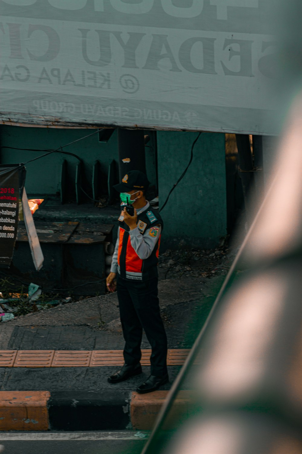 Hombre con pantalones negros de pie cerca de la pared verde durante el día