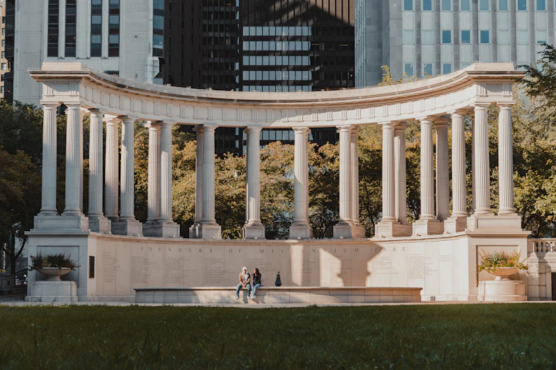 People relaxing on the grass near a white concrete building in a Chicago park