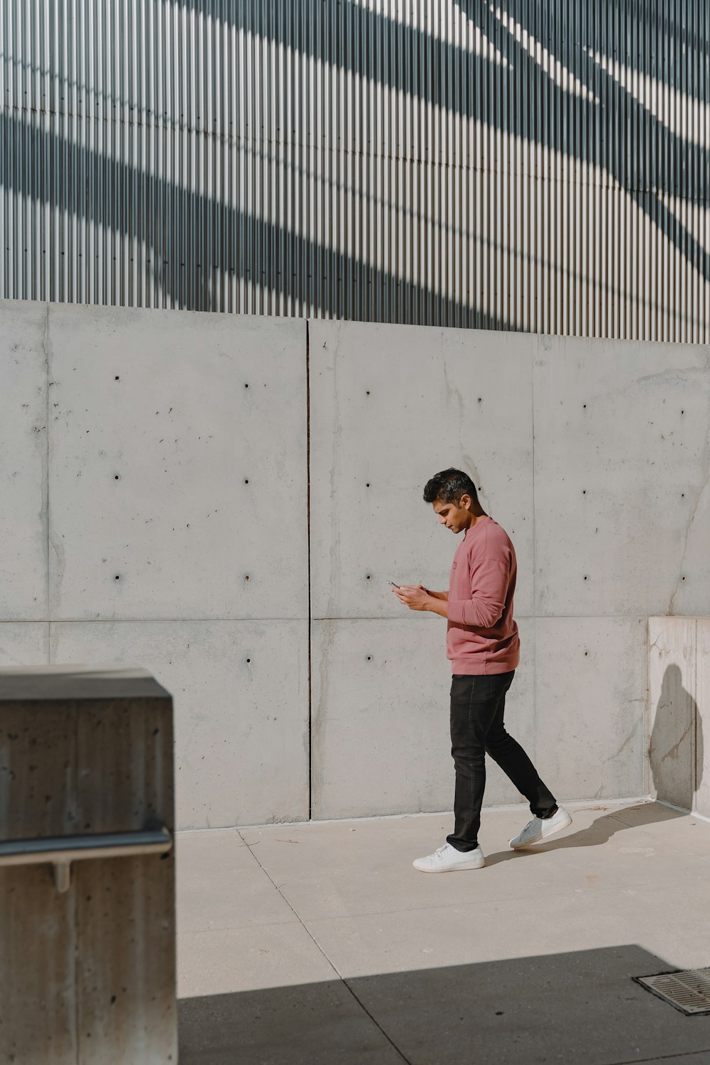 man in orange long sleeve shirt and black pants standing beside white wall