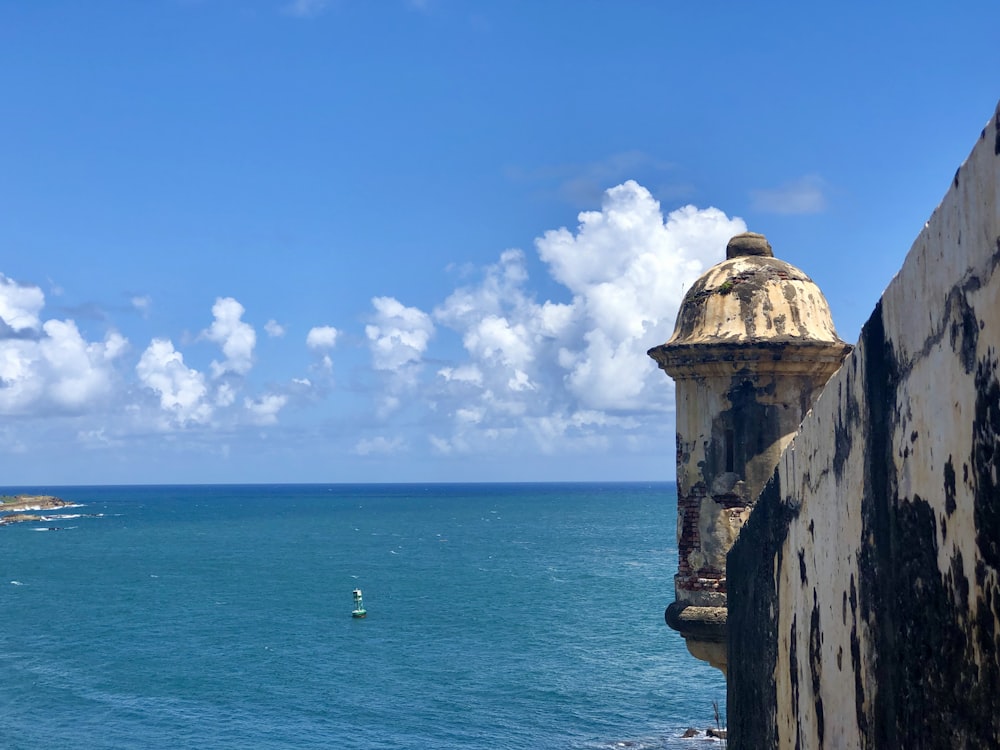 bâtiment en béton brun près de la mer sous le ciel bleu et les nuages blancs pendant la journée