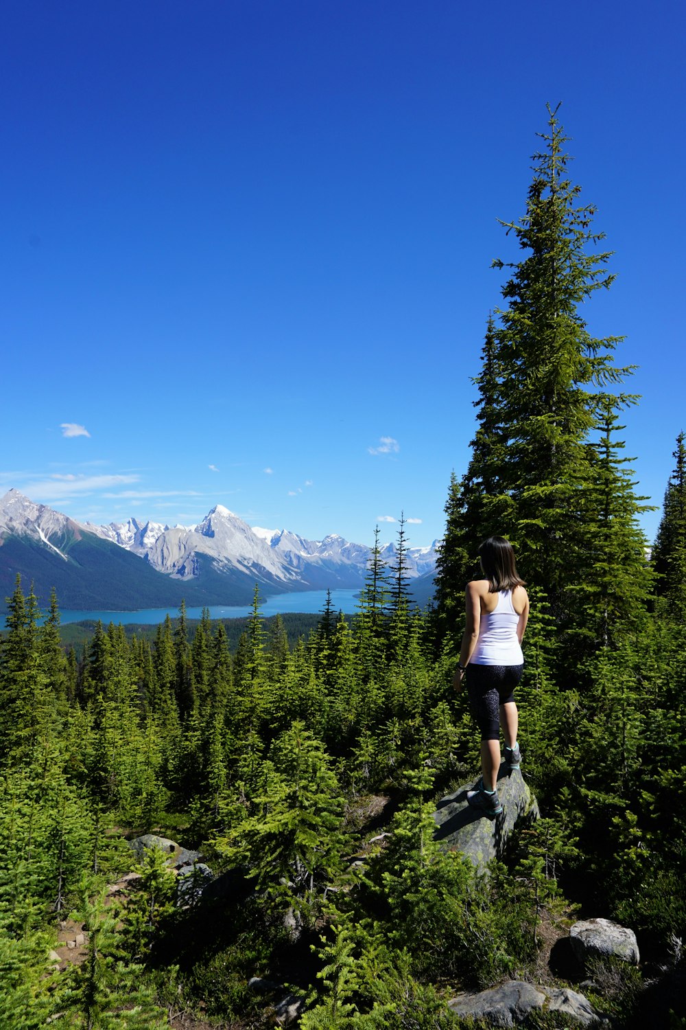 woman in black tank top and blue denim shorts standing on rocky mountain during daytime