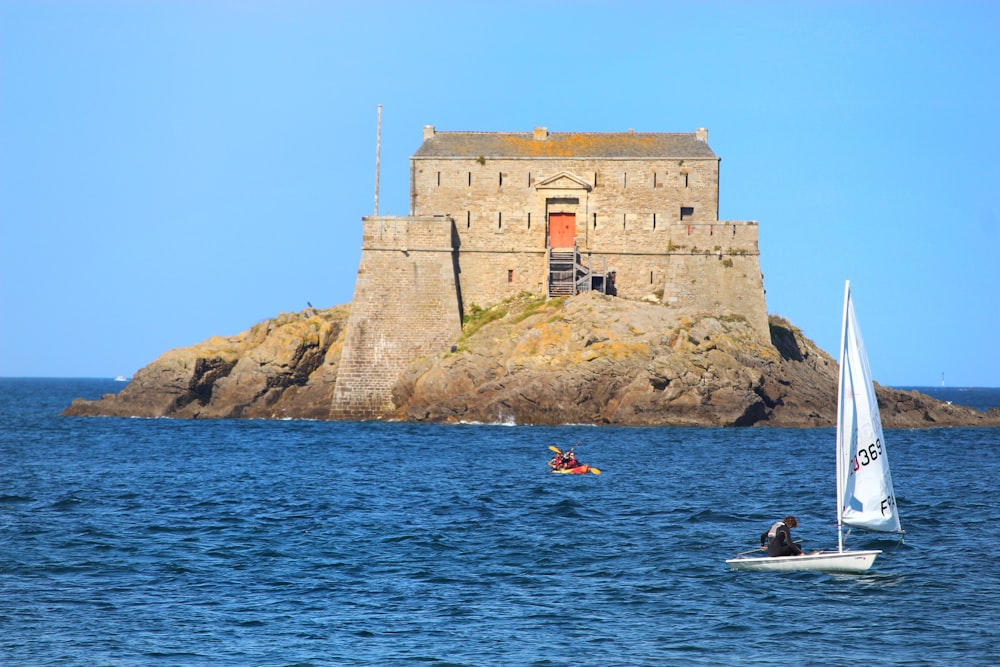 people riding on boat on sea near brown concrete building during daytime