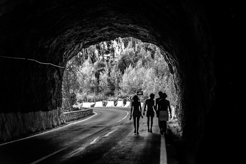 grayscale photo of people walking on tunnel