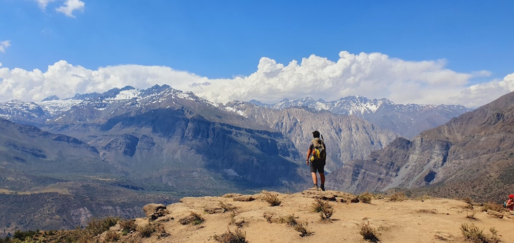 Uomo in maglietta nera in piedi sulla montagna rocciosa marrone durante il giorno