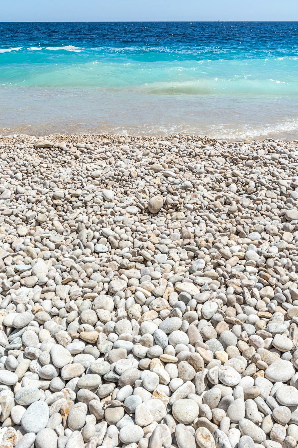 white and gray pebbles near body of water during daytime