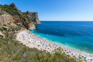 A vibrant beach scene with turquoise waters and coral-colored umbrellas under a sunny sky.