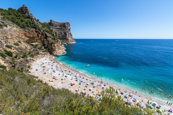 A pristine beach with turquoise waters and colorful umbrellas under a clear sky.
