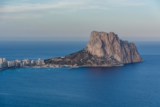 brown mountain beside blue sea under blue sky during daytime