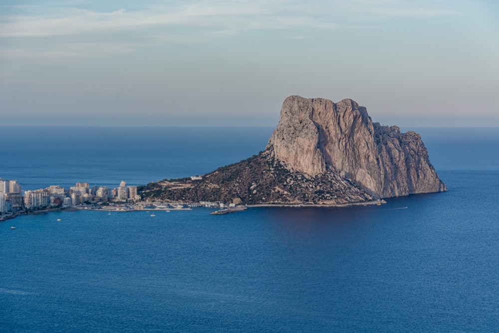 brown mountain beside blue sea under blue sky during daytime