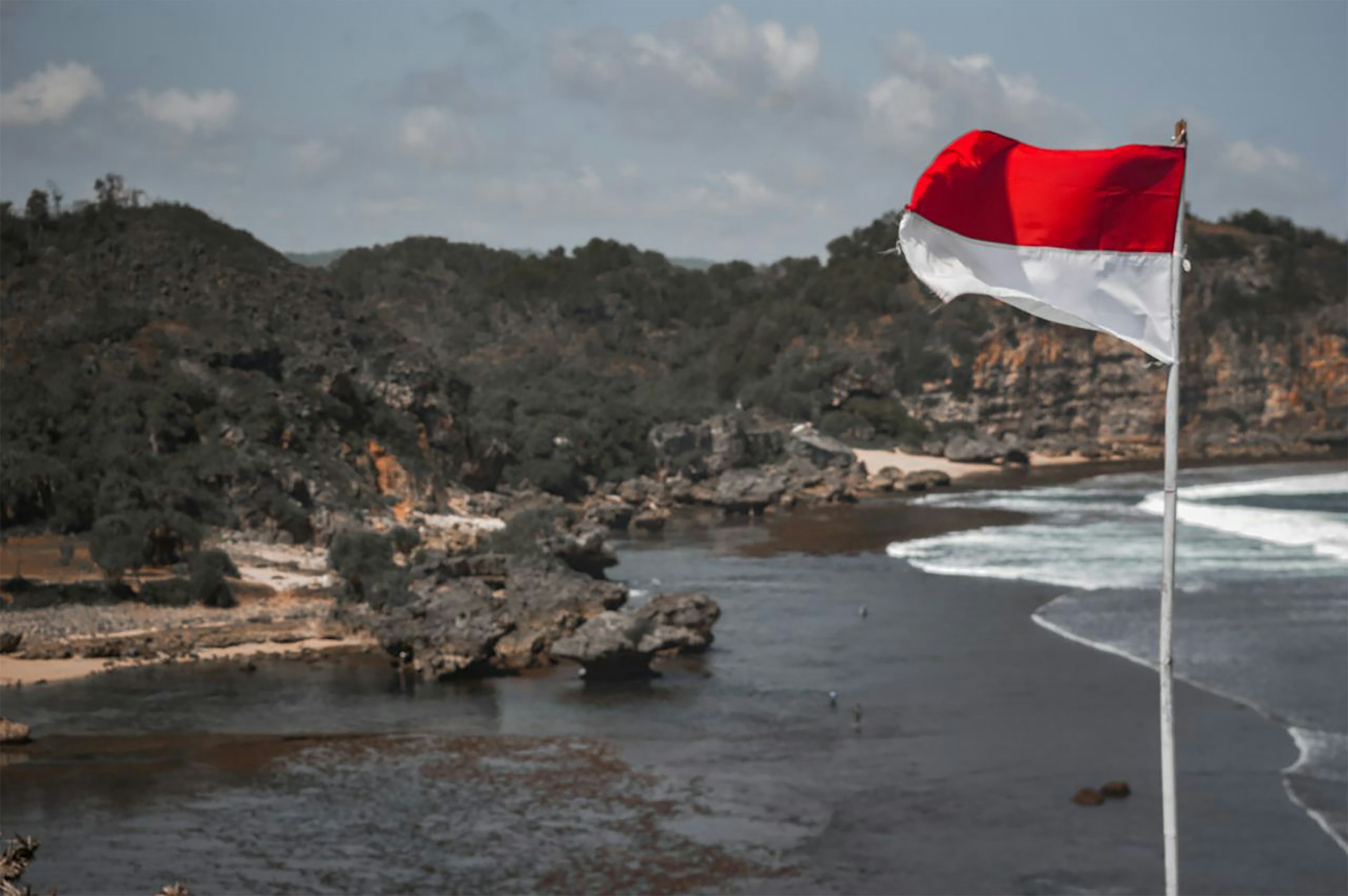 white and red flag on rocky shore during daytime