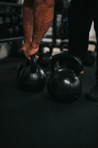 person holding black kettle bell