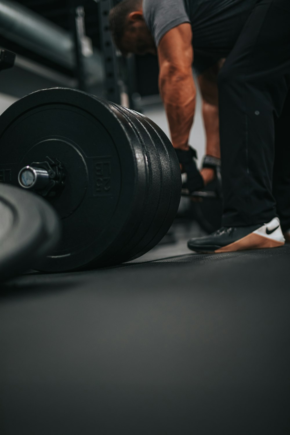 man in black shorts and black shoes carrying black dumbbell